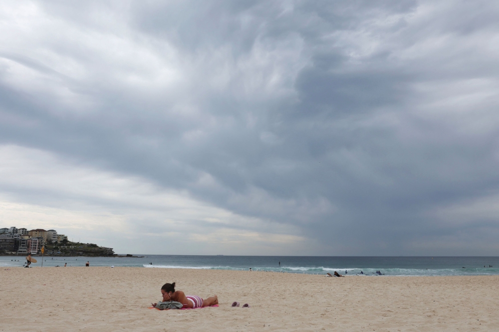 A woman sunbathes on Bondi Beach as a dark cloud moves over the horizon in Sydney October 17, 2025. — Reuters pic
