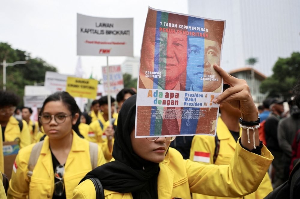 A university student holds up a poster depicting Indonesian President Prabowo Subianto and Vice President Gibran Rakabuming Raka, during a protest on the first anniversary of Subianto's administration, criticizing government policies including the free meals programme, in Jakarta, Indonesia, October 20, 2025. — Reuters pic