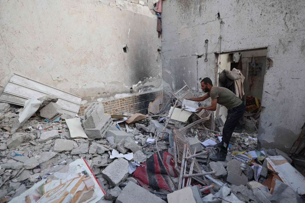 A Palestinian man inspects the damage around his home after an Israeli strike targeted the previous day the Bureij refugee camp in the central Gaza Strip on October 20, 2025. — AFP pic