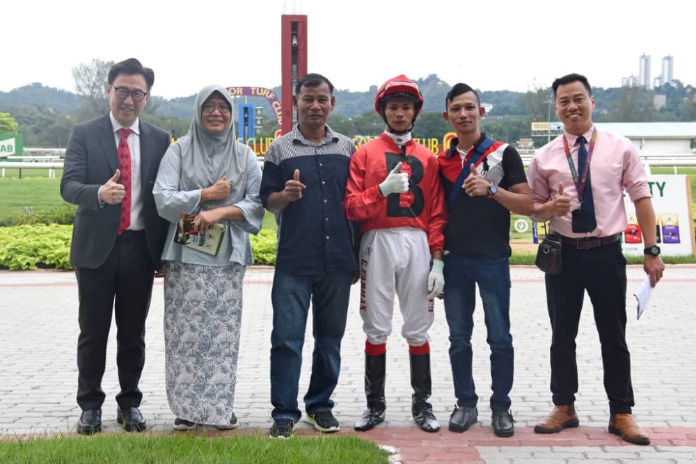 Apprentice jockey Muhammad Farhan Ghazali seen here with his father after clinching his first career victory. — Picture courtesy of Selangor Turf Club