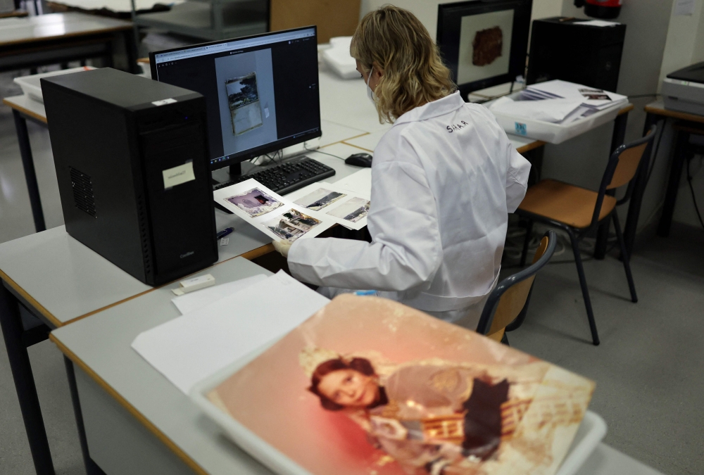 A student digitising family photographs damaged by mud. — AFP pic