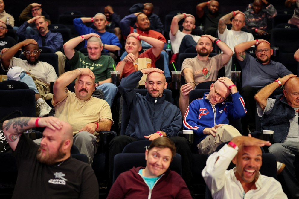 Fans with shaved heads sit in a cinema hall waiting for a free preview of Yorgos Lanthimos’s new film ‘Bugonia’, in Culver City, California, October 20, 2025. — Reuters pic