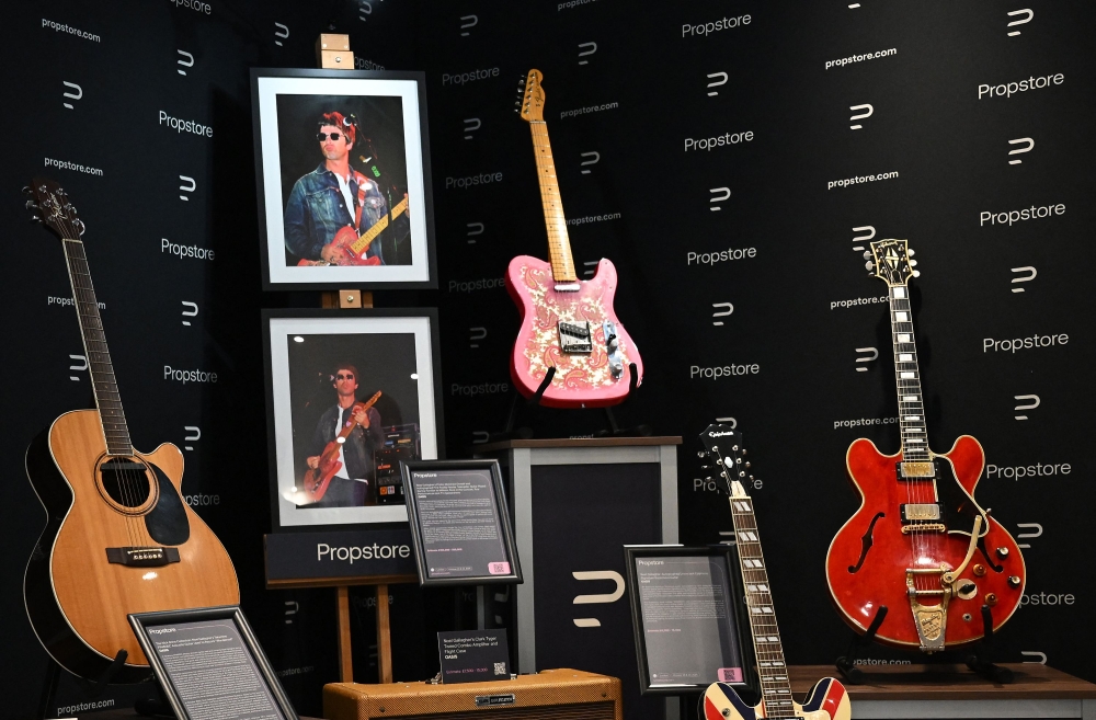 Noel Gallagher’s guitars — including the Wonderwall Takamine acoustic, a pink Fender Telecaster, and the cherry-red Gibson smashed by Liam — on display at a Propstore auction preview in London, October 21, 2025. — AFP pic