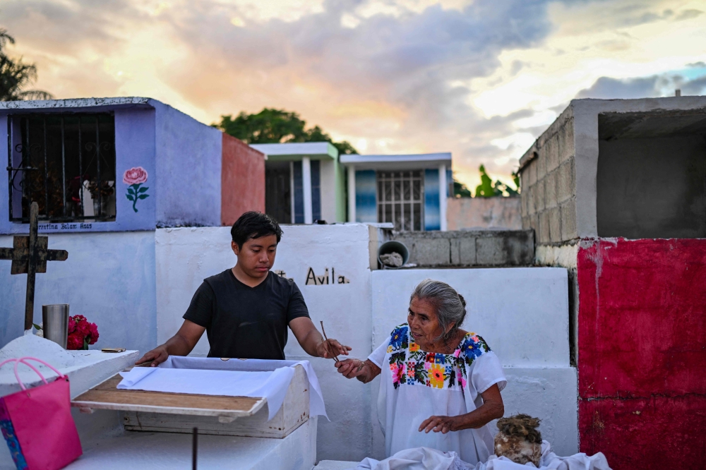 Fernando Yam and his grandmother Leonilda Poot prepare to clean the remains of a relative ahead of Day of the Dead celebrations at the Pomuch cemetery, Campeche state, Mexico on October 18, 2025. — AFP pic