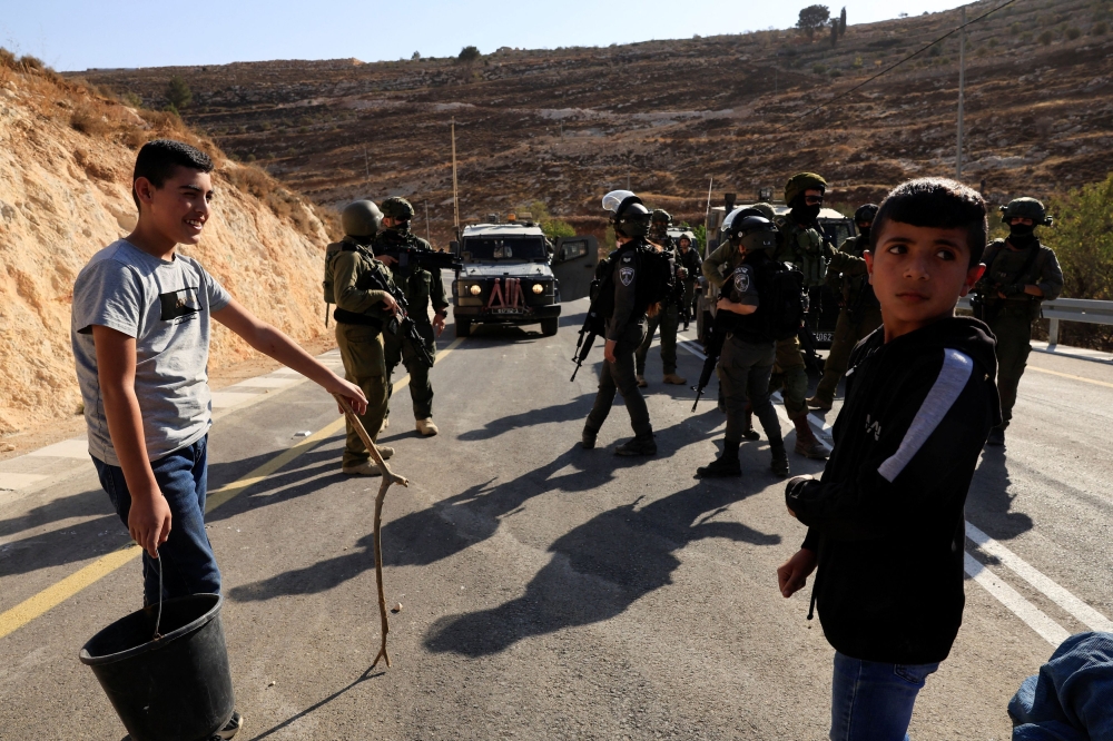 Members of the Israeli forces stand guard as they block the access of Palestinians and foreign activists to olive trees during the olive harvest, near Hebron, in the Israeli-occupied West Bank, October 23, 2025. — Reuters pic