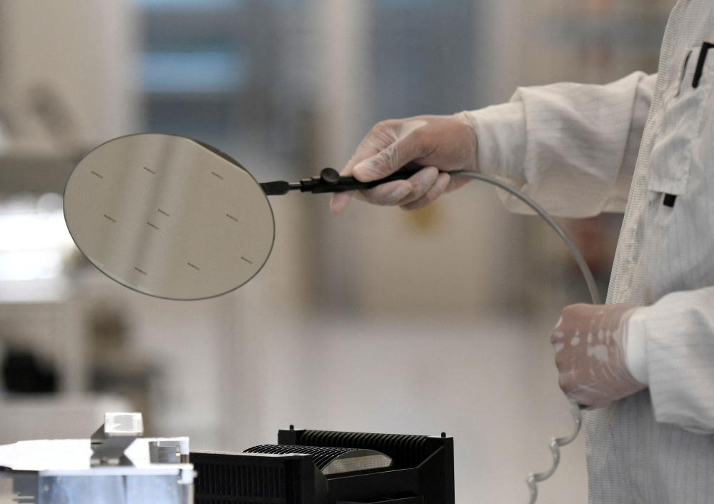 An employee works with a wafer in a production line of Dutch semiconductor company Nexperia, in Hamburg, Germany June 27, 2024. — Reuters pic