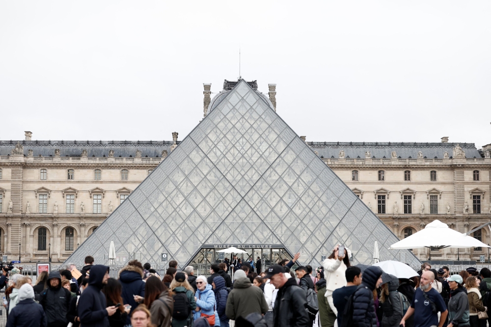 Visitors stand near the glass Pyramid of the Louvre Museum as the museum remains closed the day after a spectacular jewel heist by thieves who broke into the landmark by using a crane and smashing an upstairs window, stealing priceless jewelry from an area that houses the French crown jewels before escaping on motorbikes, in Paris, France, October 20, 2025. — Reuters