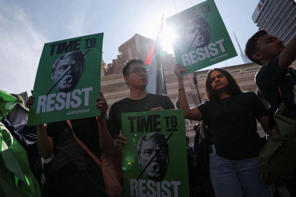 Protesters hold placards during a protest against US President Donald Trump’s attendance at the 47th Asean Summit, at Dataran Merdeka, Kuala Lumpur, October 26, 2025. — Reuters pic 