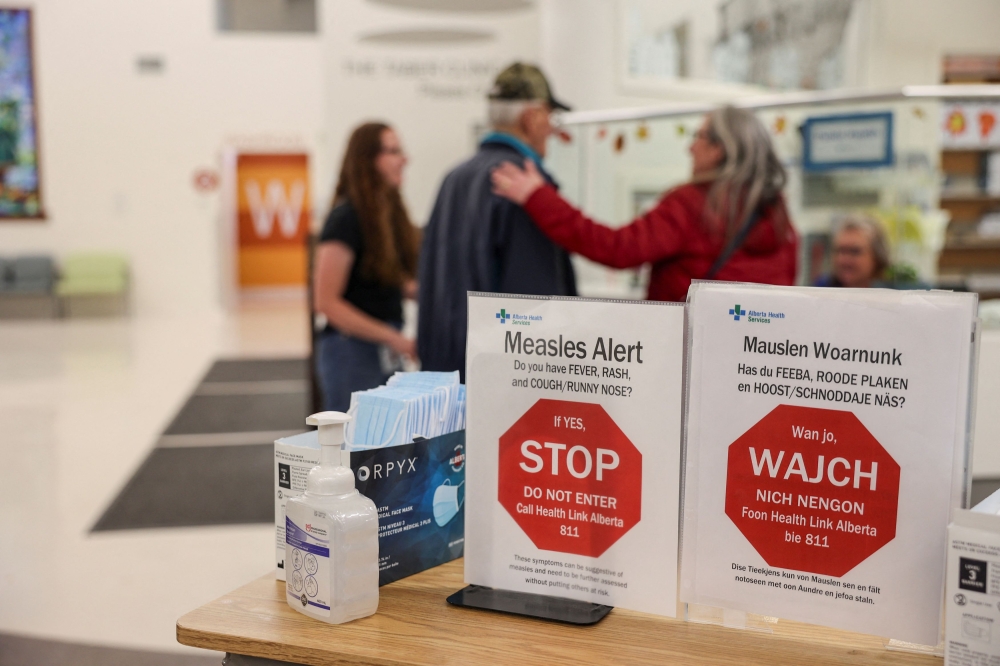People stand near healthy awareness posters related to the measles outbreak during a public health awareness campaign, at the Taber Health Centre, in the largely Mennonite community of Taber, Alberta October 27, 2025. — Reuters pic