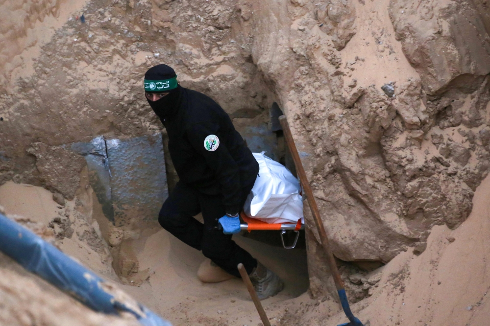 A Hamas fighter carries a body retrieved from a tunnel in an area north of Khan Yunis in the southern Gaza Strip on October 28, 2025. Israel’s military on October 28 accused Hamas of staging its search for the remains of a Gaza hostage body, one of 28 the group had agreed to hand over under a ceasefire deal. — AFP pic 