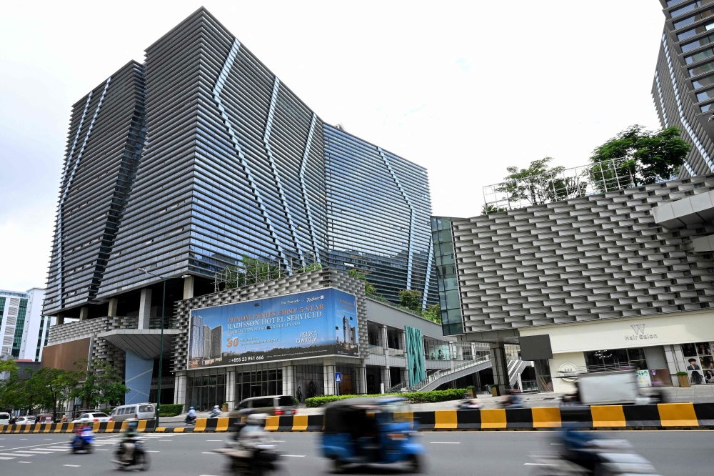Vehicles drive past the Prince International Plaza in Phnom Penh on October 15, 2025. — AFP pic