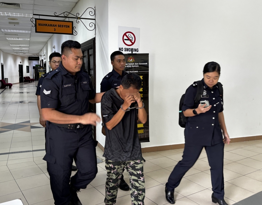 The stepfather is escorted from the courtroom at the Kuching Court Complex. — The Borneo Post pic