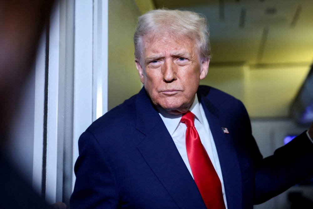 US President Donald Trump speaks to members of the media on board Air Force One en route to the US, October 30, 2025. — Reuters pic