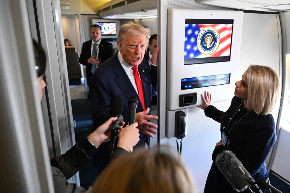 US President Donald Trump speaks to reporters aboard Air Force One before departing Joint Base Andrews, Maryland, on October 31, 2025. — AFP pic