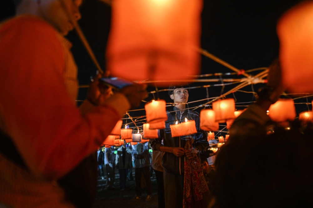 This picture taken on October 30, 2025 shows participants holding candles as they prepare for the release of a hot air balloon loaded with fireworks during the Tazaungdaing Lighting Festival in Taunggyi in Myanmar's northeastern Shan State. — AFP pic