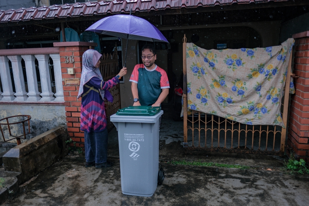 Johor Bahru resident Ahmad Rizal Akiah (right) and his wife, Syobiraah Mat Saad, carry a water bin into their home in Taman Pelangi following an unscheduled supply disruption caused by Sungai Johor pollution, on November 2, 2025. — Bernama pic