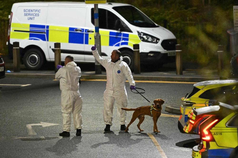 A police forensics officer holds a dog at Huntingdon Station in Huntingdon, eastern England, on November 1, 2025, following a stabbing on a train. UK police said they had arrested two suspects Saturday as ‘a number of people’ were taken to hospital after a stabbing on a train in Cambridgeshire, eastern England. — AFP pic 