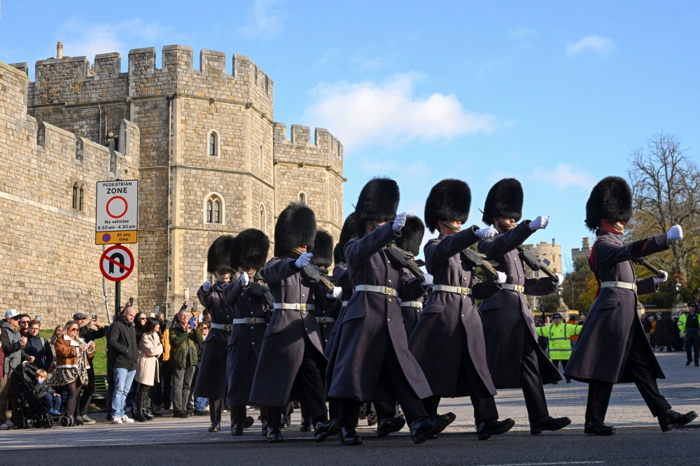 Guards march with Windsor Castle in the background, after Britain's King Charles stripped his younger brother, Andrew, of his title of prince and forced him out of his Windsor home, Buckingham Palace said on Thursday, seeking to distance the royals from him over his links to the Jeffrey Epstein scandal, in Windsor November 1, 2025. — Reuters pic