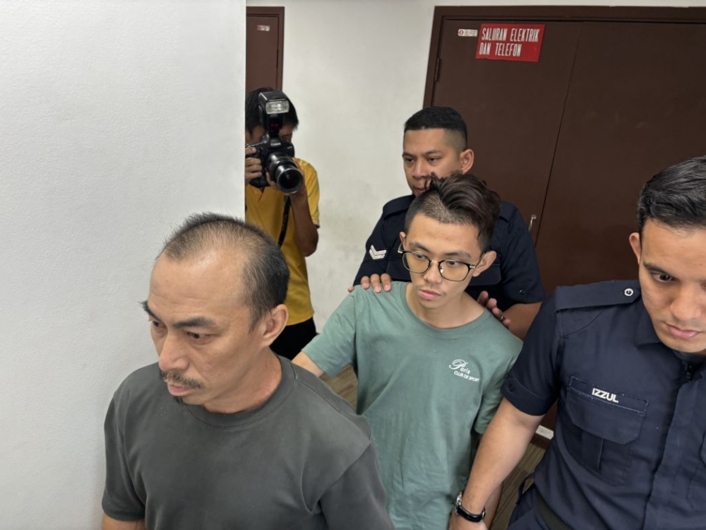 Wong Jiun Wei (in green) and Lim Boon Ping (grey) are brought to the Magistrates Court in Ipoh, on Nov 4, 2025. — Picture by John Bunyan