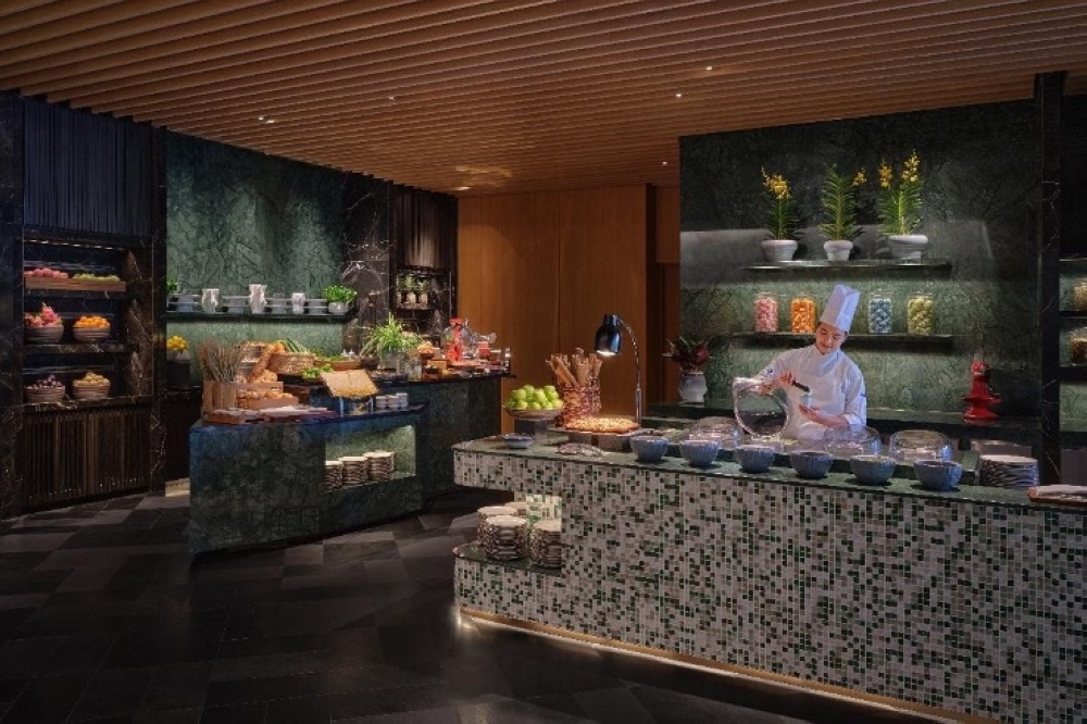 A chef prepares desserts at the newly unveiled dessert bar at Midtown Brasserie, featuring a spread of artisanal sweets, fresh produce and baked treats.