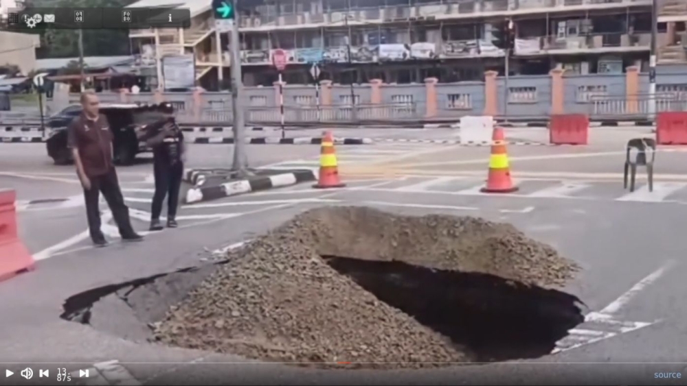 A still from an online video shows people observing a sinkhole on Jalan Dato Ismail Hashim in Sungai Ara, Bayan Lepas.