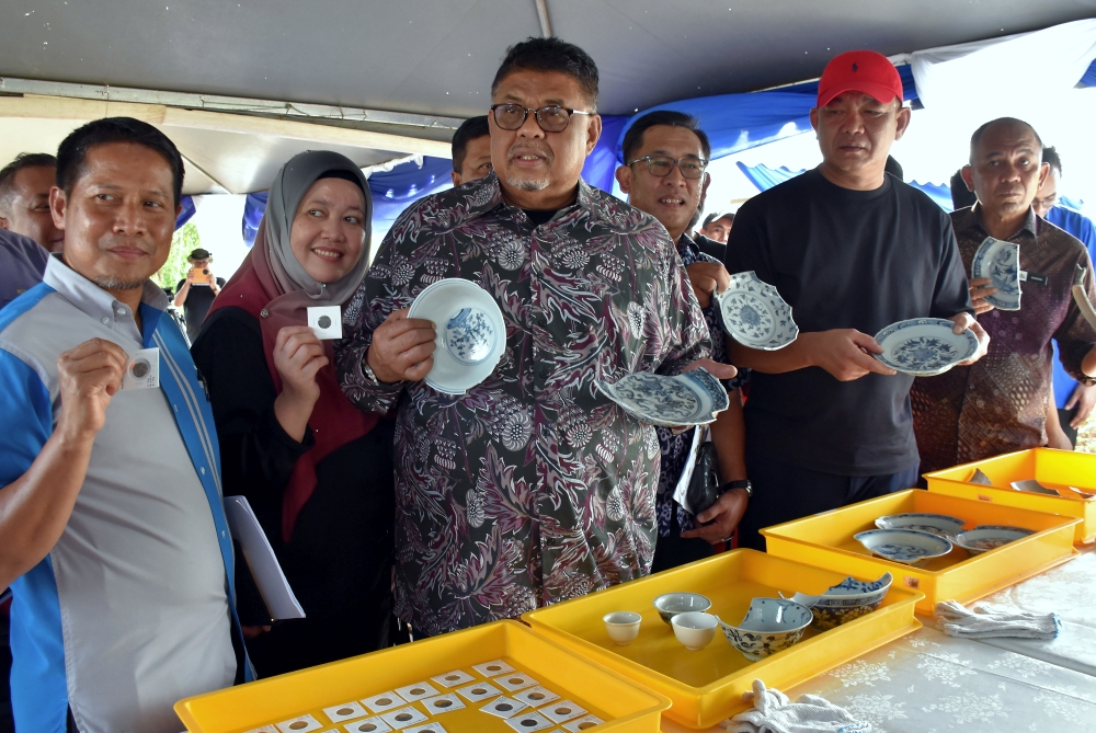 Melaka Chief Minister Datuk Seri Ab Rauf Yusoh and National Heritage Department director-general Mohamad Muda Bahadin inspect porcelain and old coins discovered on Pulau Melaka. — Bernama pic