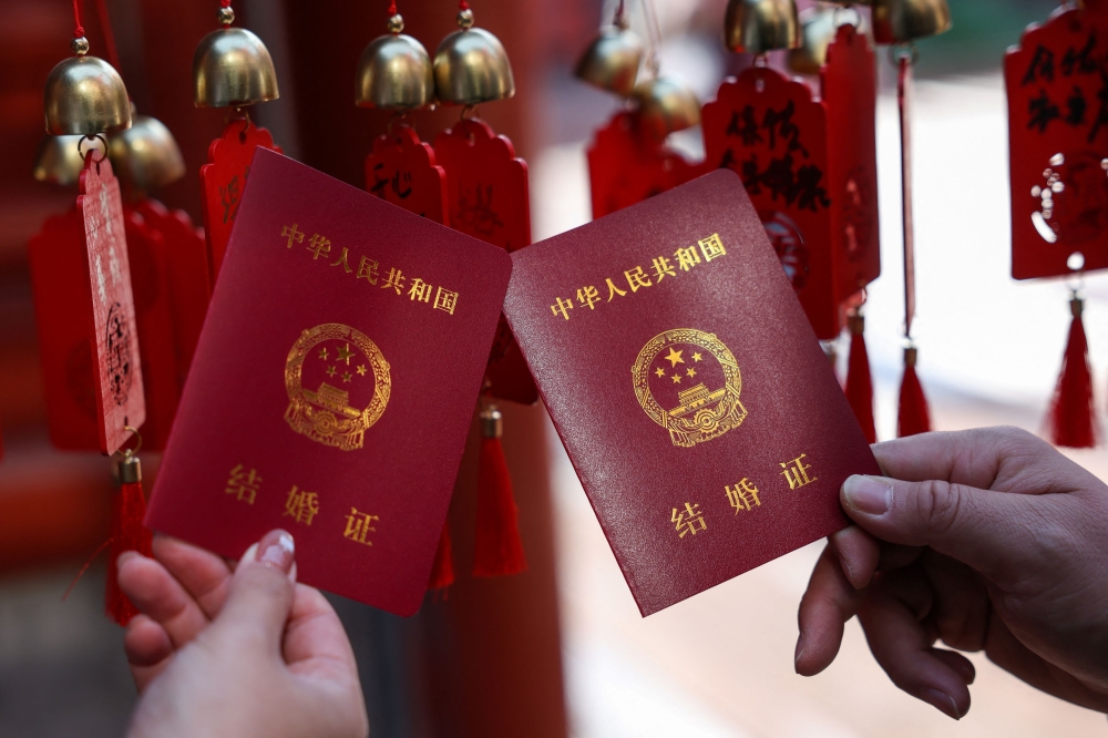 A newlywed couple holds their marriage certificates after they registered at the Huguo Guanyin Temple, in Beijing, China, October 28, 2025. — Reuters pic 