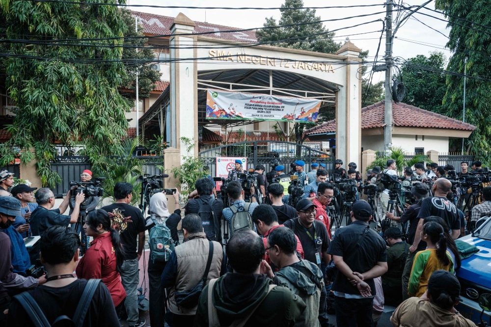 Security officers on guard as journalists gather outside a Jakarta school where a blast injured dozens on November 7, 2025. — AFP pic