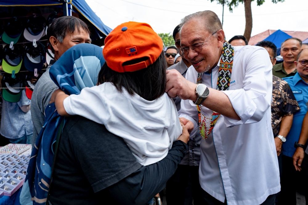 Prime Minister Anwar Ibrahim mingles with visitors during a walkabout at the Gaya Street Sunday Market in Kota Kinabalu, where he also stopped for ‘nasi lemak’ before officiating the ‘Rancakkan Madani Sabah’ programme at SICC. — Picture via Facebook/Anwar Ibrahim