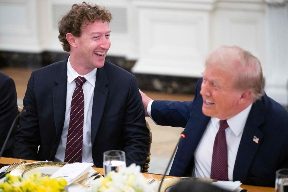 US President Donald Trump slaps Meta CEO Mark Zuckerberg (left) on the back as he hosts tech leaders for a dinner in the State Dining Room of the White House in Washington, DC, on September 4, 2025. — AFP pic