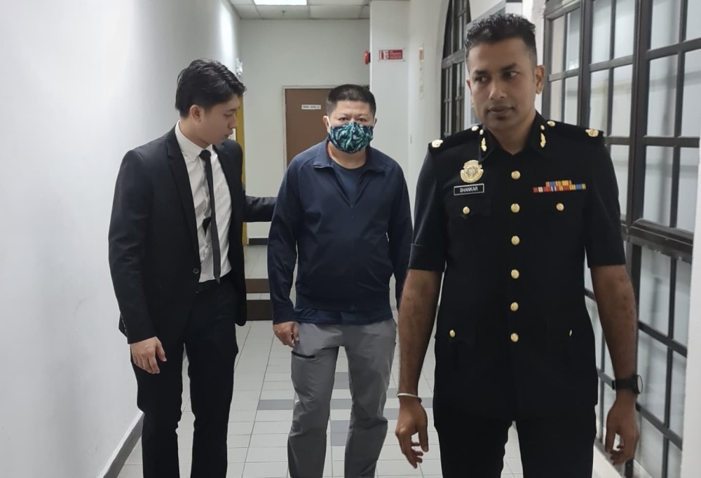 Company director Chen Zhenlong (centre) was fined RM20,000 by the Johor Bahru Sessions Court today for deceiving the Johor Department of Environment (DOE) during a 2022 investigation into his company’s purchase of plastic containers. — Picture by Ben Tan