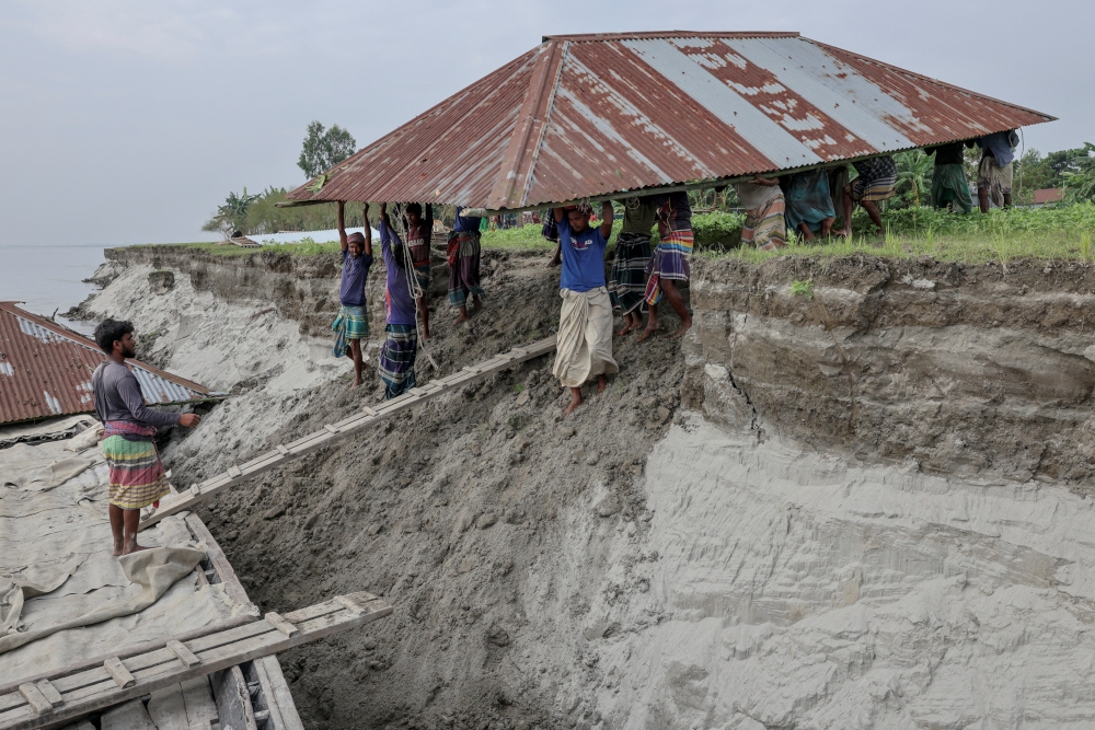 People carry the roof of the house belonging to Nurun Nabi, 30, to load onto a boat, after he was forced to relocate to another island due to erosion caused by the Brahmaputra River, in Kurigram, Bangladesh, October 29, 2025. — Reuters pic 