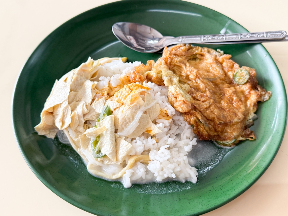 Pick what you like from the spread of cooked dishes like omelette or beancurd skin and mushrooms with coconut milk to go with your plate of rice. — Picture by Lee Khang Yi

