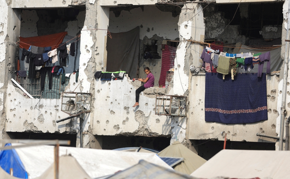 A displaced Palestinian girl sits on a wall of a damaged school where she has taken shelter, during a ceasefire between Israel and Hamas, in Gaza City, November 11, 2025. — Reuters pic