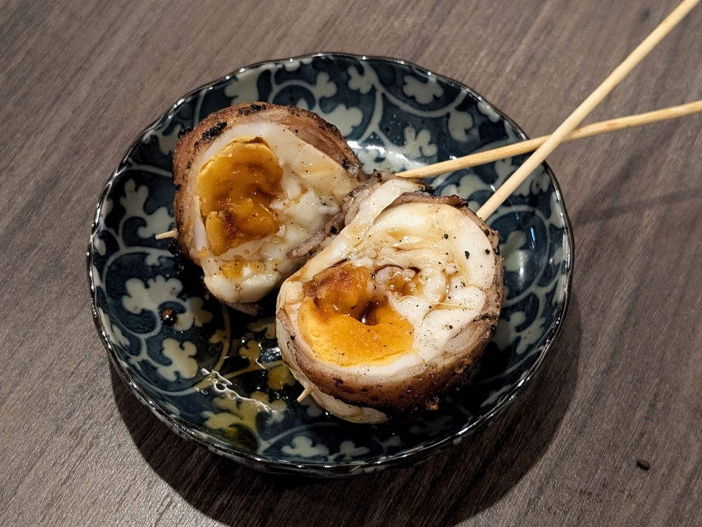 An inventive skewer of a boiled egg wrapped in pork belly. — Picture by Ethan Lau