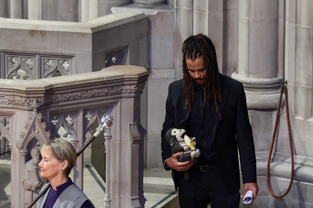 Jane Goodall’s grandson Merlin Van Lawick carries a stuffed toy of a monkey during the funeral service. — Reuters pic