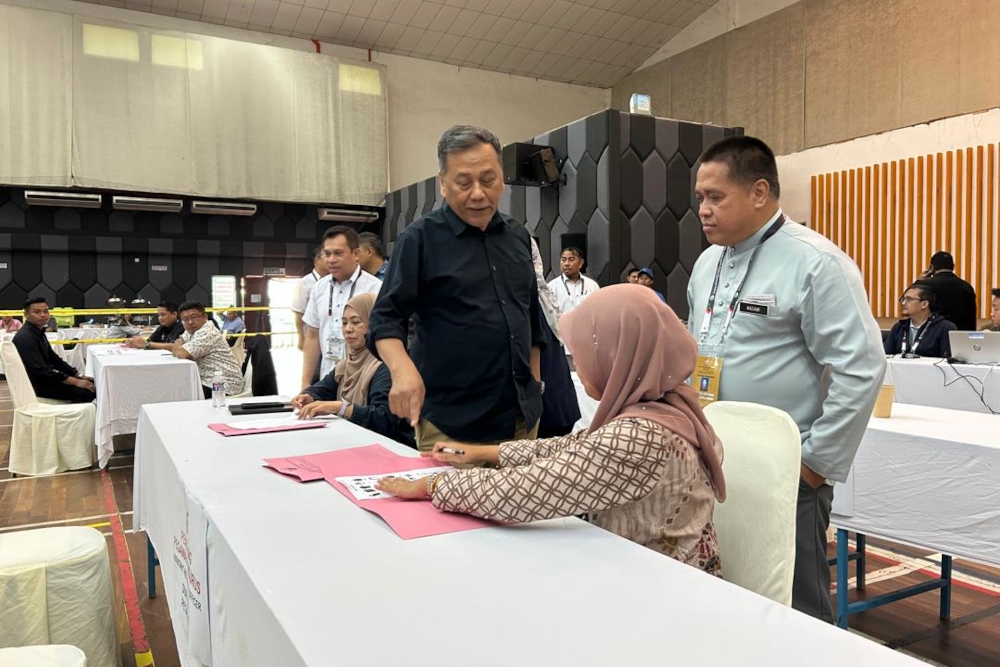 Election Commission (EC) chairman Datuk Seri Ramlan Harun discusses a point with an officer at the nomination centre in Kota Kinabalu, November 14, 2025. — The Borneo Post pic 