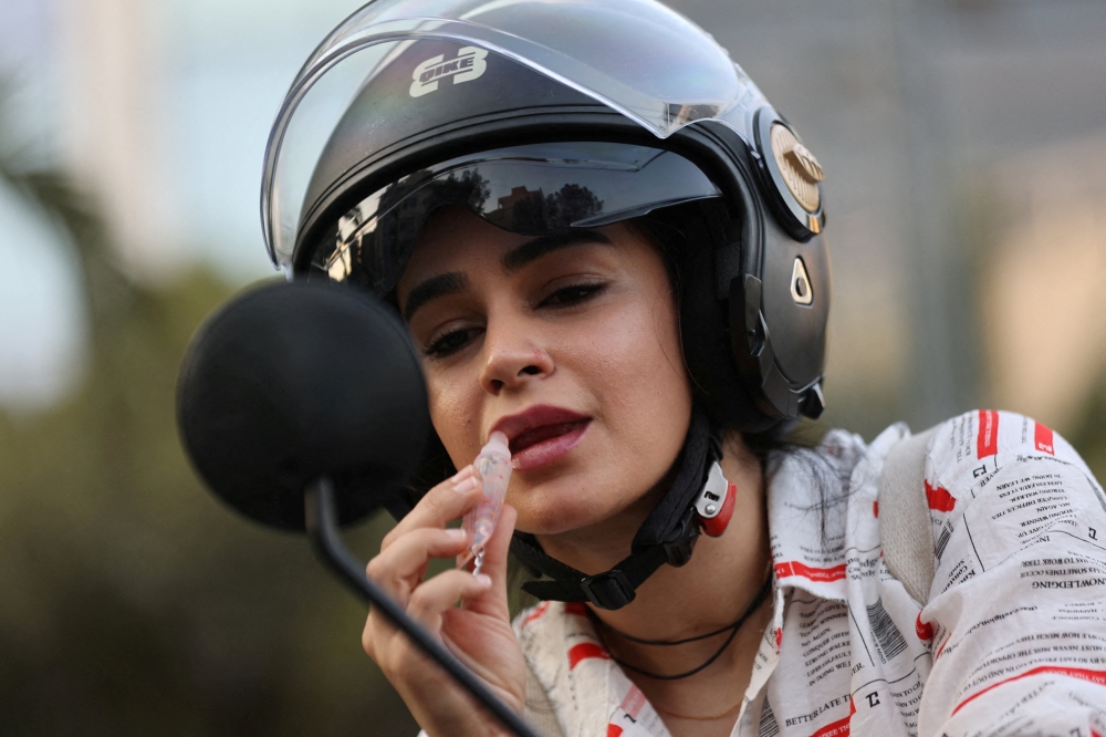 An Iranian woman, Bahareh, applies lipstick while looking at herself in the mirror of her motorcycle while female motorcycling is still not officially legal, in Tehran, Iran, September 8, 2025. — Reuters pic 