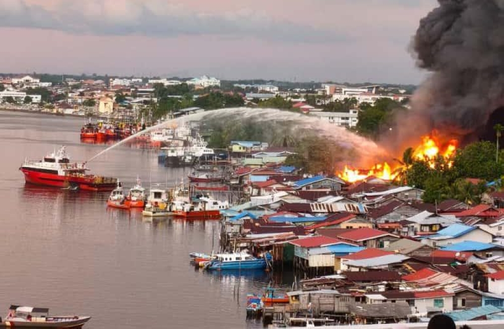 The firefighting efforts were assisted by a vessel from a shipping company that helped spray water from the Miri River. — The Borneo Post pic