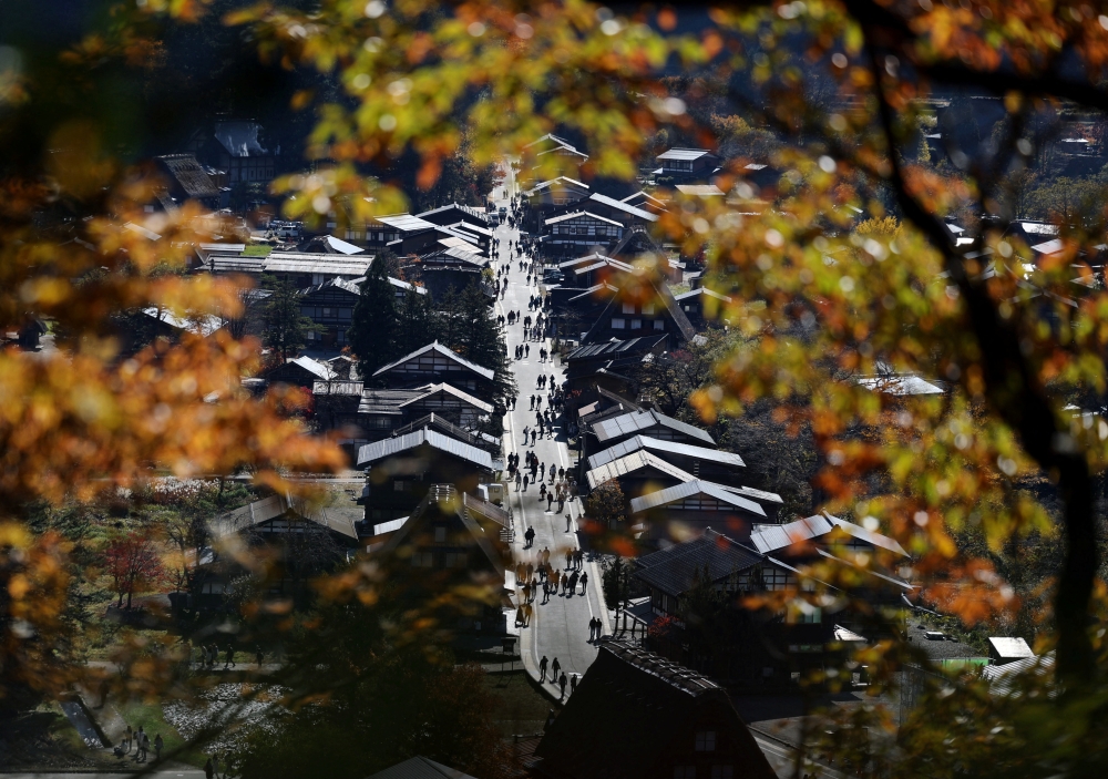 Visitors strolling next to traditional Gassho-style houses are seen through autumn leaves at Shirakawa-go, a popular tourist spot and one of Japan’s Unesco World Heritage sites, in Shirakawa village, Gifu Prefecture, November 15, 2025. — Reuters pic