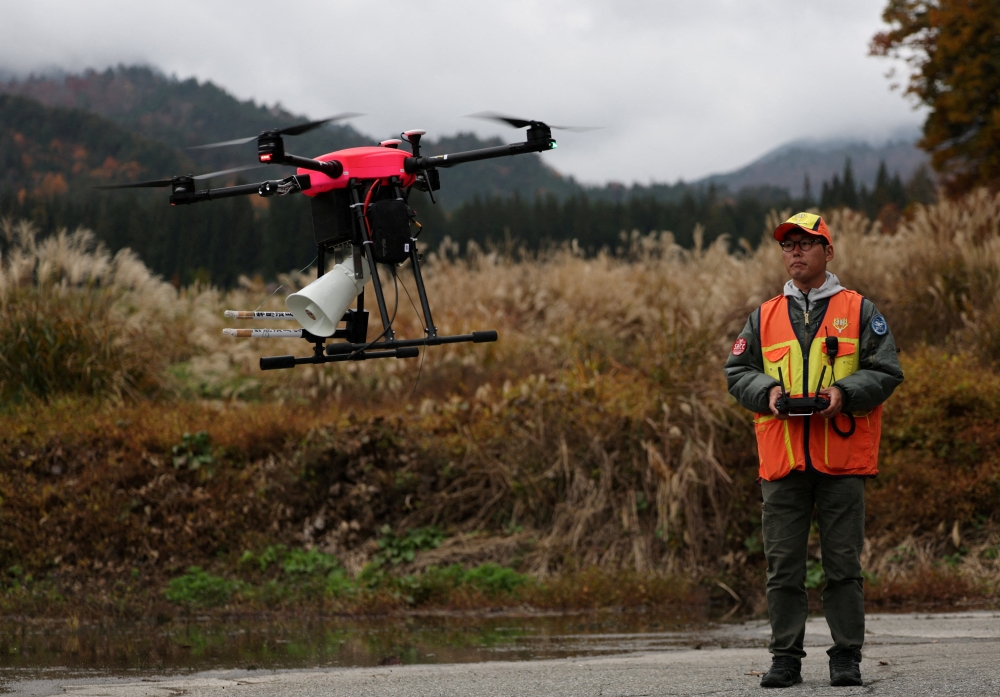 A staff member of Kyoto-based Aero Japan controls their drone UD4JH, also called ‘Hunting Drone’, which was developed by their company and equipped with firecrackers and loudspeakers emitting the sounds of barking dogs as they conduct an operation to stop bears from ransacking apple and peach orchards, at Fruit Park Kurouchi Orchard in Hida, Gifu Prefecture, November 14, 2025. — Reuters pic