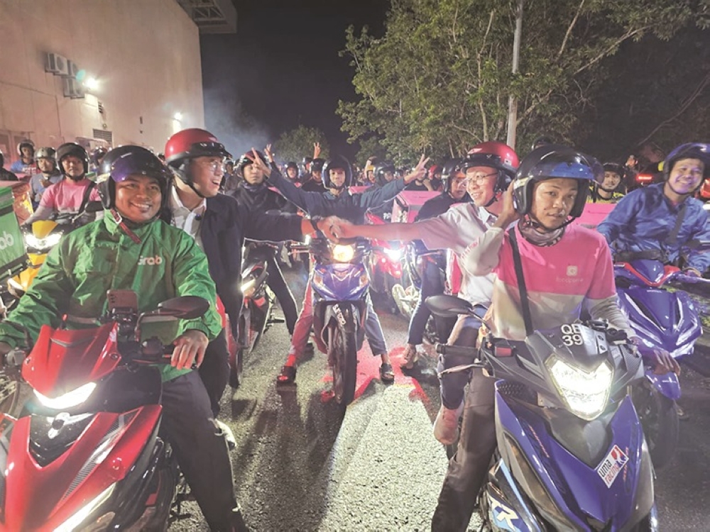 Sim and Chan ride with gig workers during the session in Tanjung Aru. — Daily Express pic