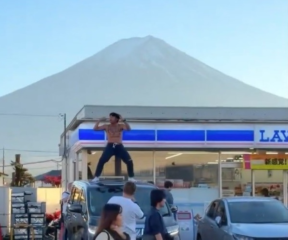 A still from the controversial clip showing Thai YouTuber Jack Papho dancing shirtless on a parked car outside the famed Fuji-view Lawson in Fujikawaguchiko, a spot already strained by overtourism.