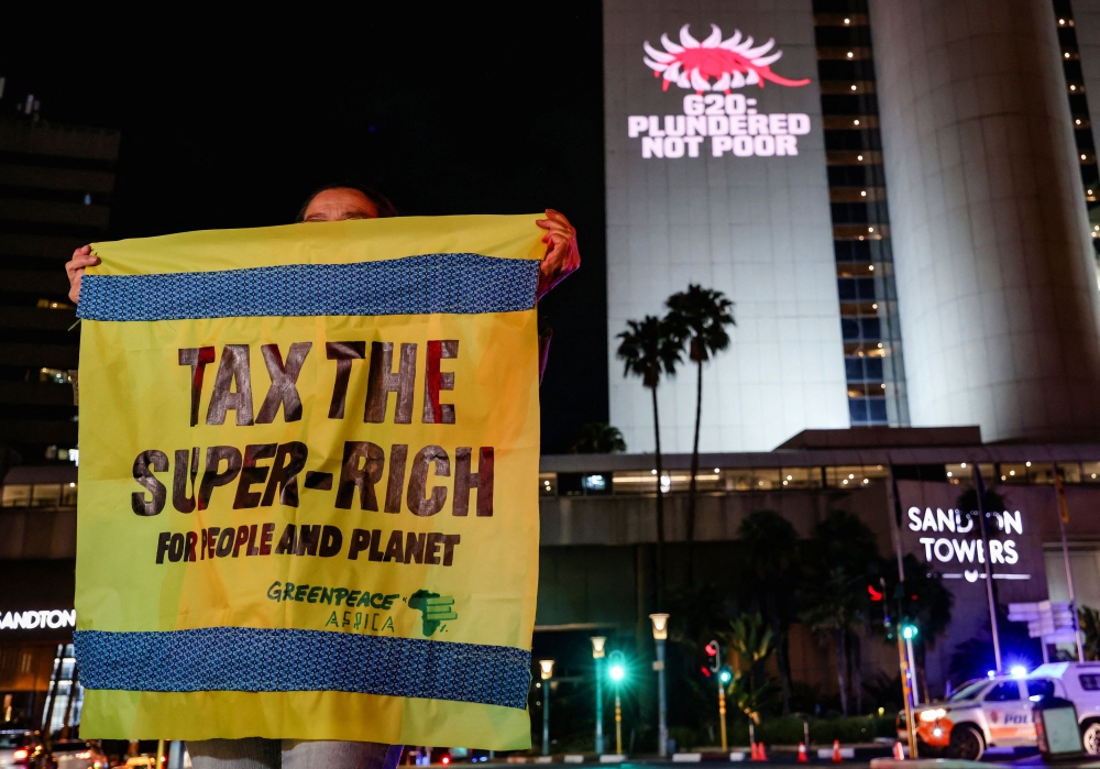 A Greenpeace activist holds a banner as she joins a Glasgow Actions Team projection calling for bold debt reform, stronger climate action and urgent responses to the global development crisis as leaders prepare for the first G20 summit hosted in Africa, in Johannesburg, South Africa, November 19, 2025. — Reuters pic 