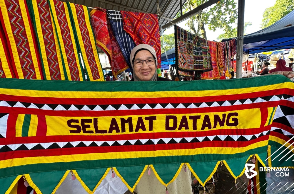 A trader at the Kota Belud ‘tamu’ in Sabah holds up handicrafts for sale. — Bernama pic