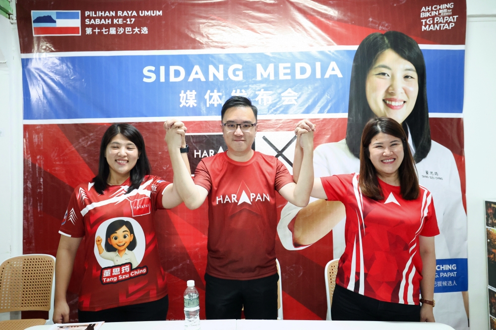 DAP Sabah chairman Datuk Phoong Jin Zhe (centre) raises the hands of Pakatan Harapan candidates Tang Szu Ching (left) for the Tanjung Papat state seat and Vivian Wong for Elopura as a show of support during a press conference. — Bernama pic