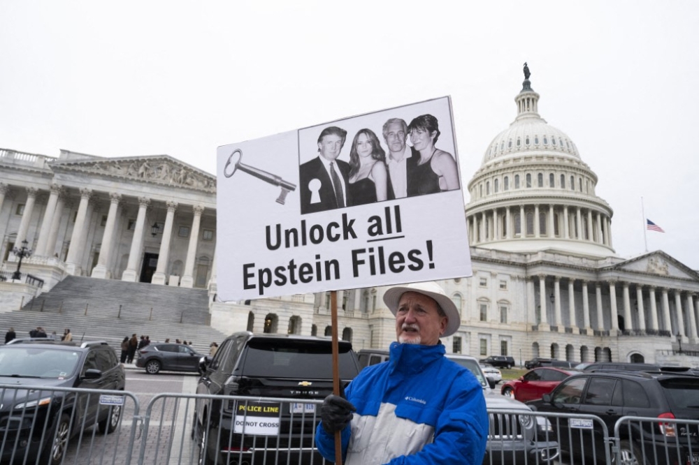 A protester holds a placard November 18, 2025 in Washington, DC after the US House of Representatives voted 427-1 to approve the Epstein Files Transparency Act and the release of documents and files. — AFP pic