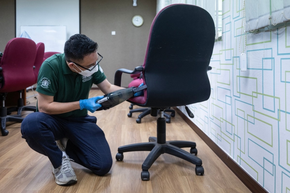 This photo taken on October 8, 2025, shows a researcher using a vacuum to recover bed bugs from a chair at a laboratory of the Science University of Malaysia (USM) in George Town. — AFP pic