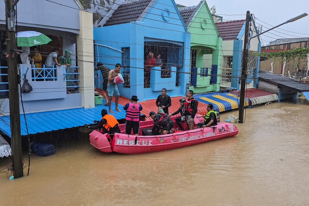 Members of rescue teams distribute supplies to stranded people in a flooded area in Hat Yai November 24. — Reuters pic
