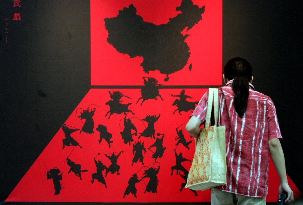 A visitor stands in front of an exhibit of a stage set featuring Chinese warriors fighting on a map of China and Taiwan on the frontline island of Quemoy, Taiwan, September 10, 2004. — Reuters file pic